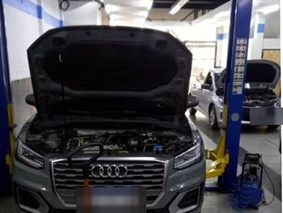 Audi con el capot abierto entre las columnas del elevador del taller